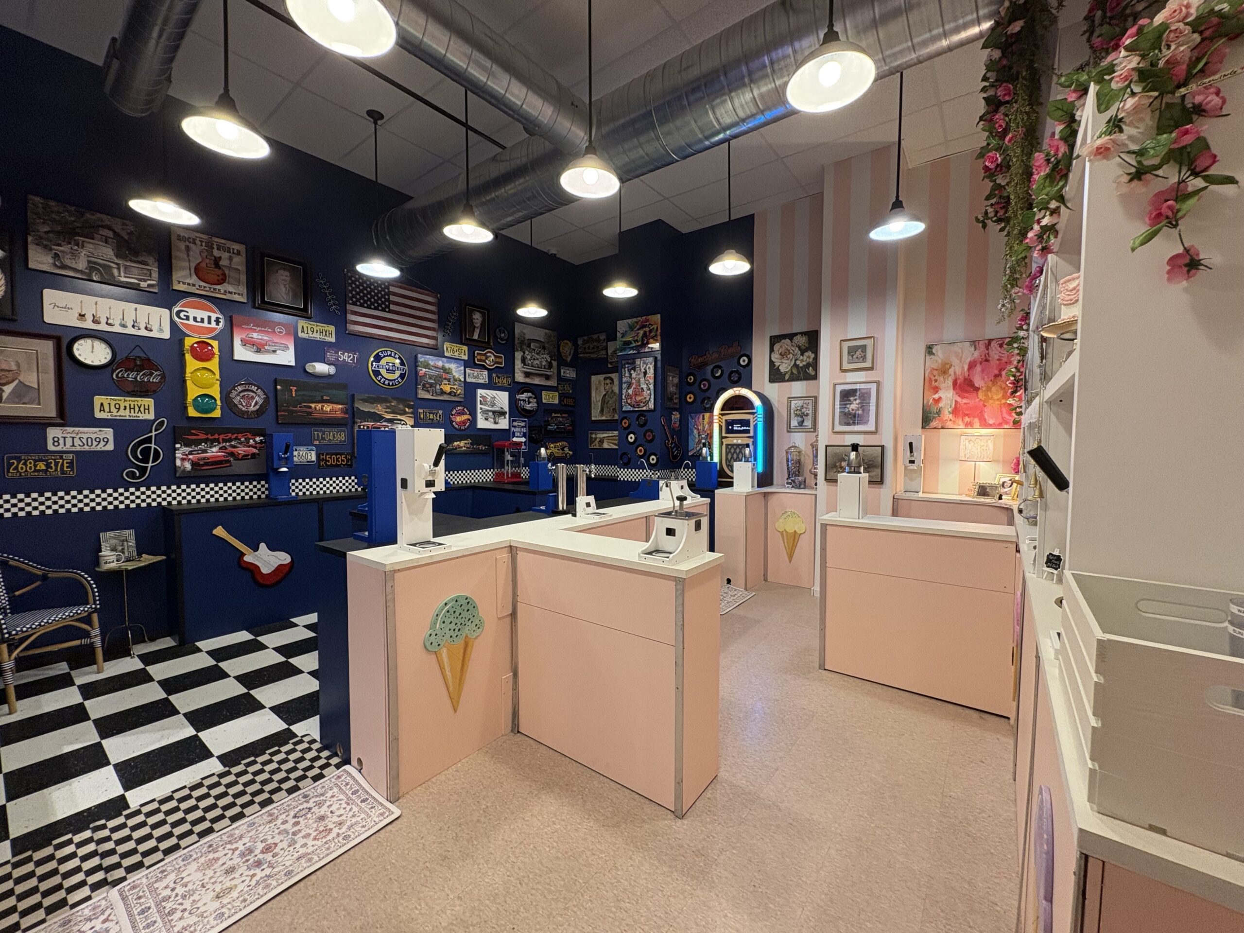 Interior of an ice cream shop featuring a retro-themed wall with license plates, checkered floor, and light pink service counters.