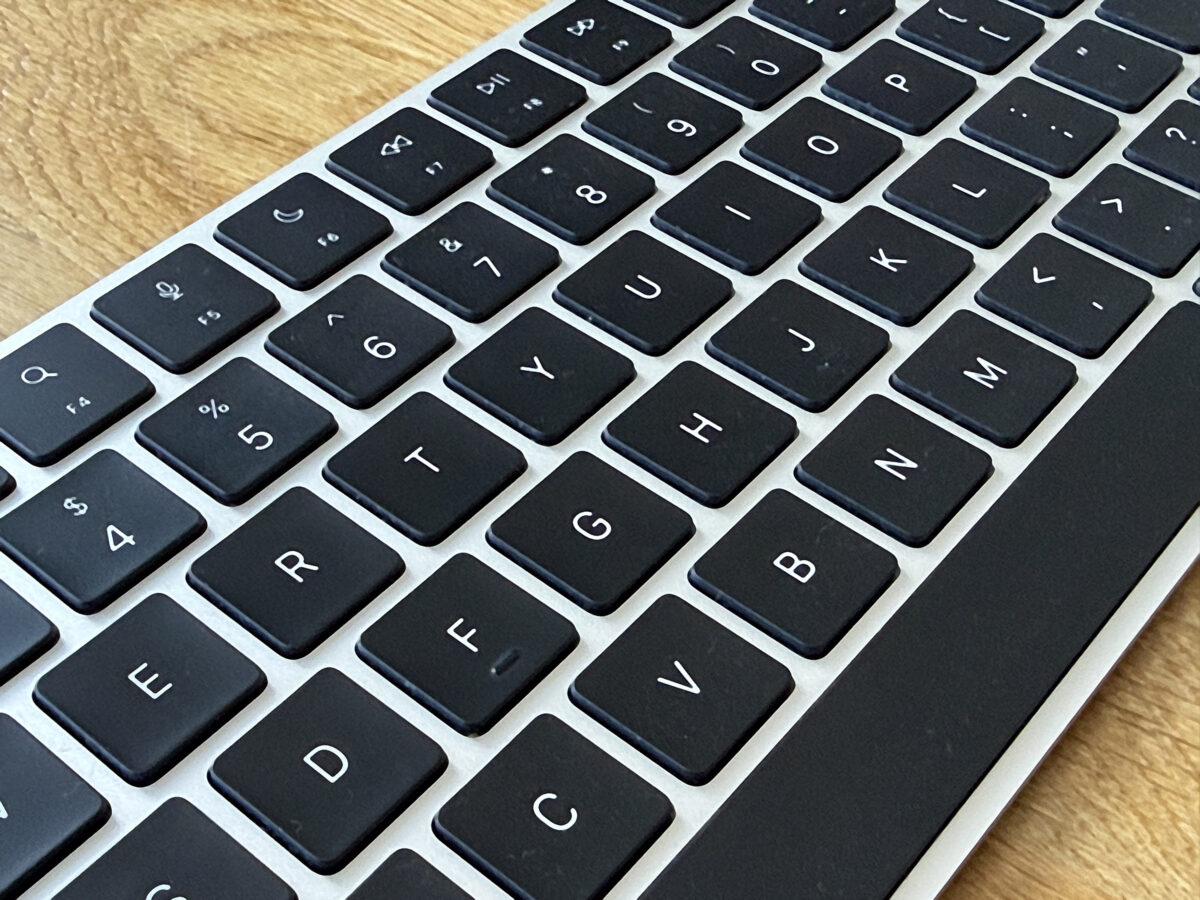 A close-up of a computer keyboard with black keys and white letters resting on a wooden surface.