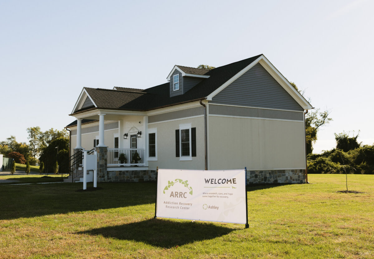 A one-story building with a front porch stands behind a sign that reads: “Welcome, ARRC Addiction Recovery Research Center, where research, care, and hope come together for recovery.”