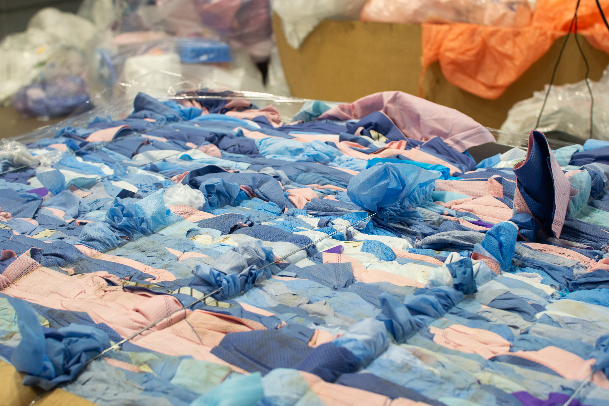 A large, shrink-wrapped bale of discarded blue and pink surgical masks.