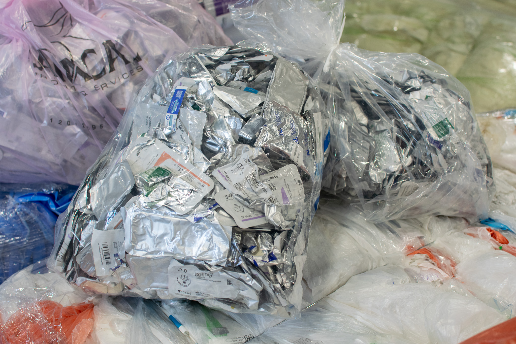 Clear plastic bags filled with discarded medical packaging and foil wrappers.