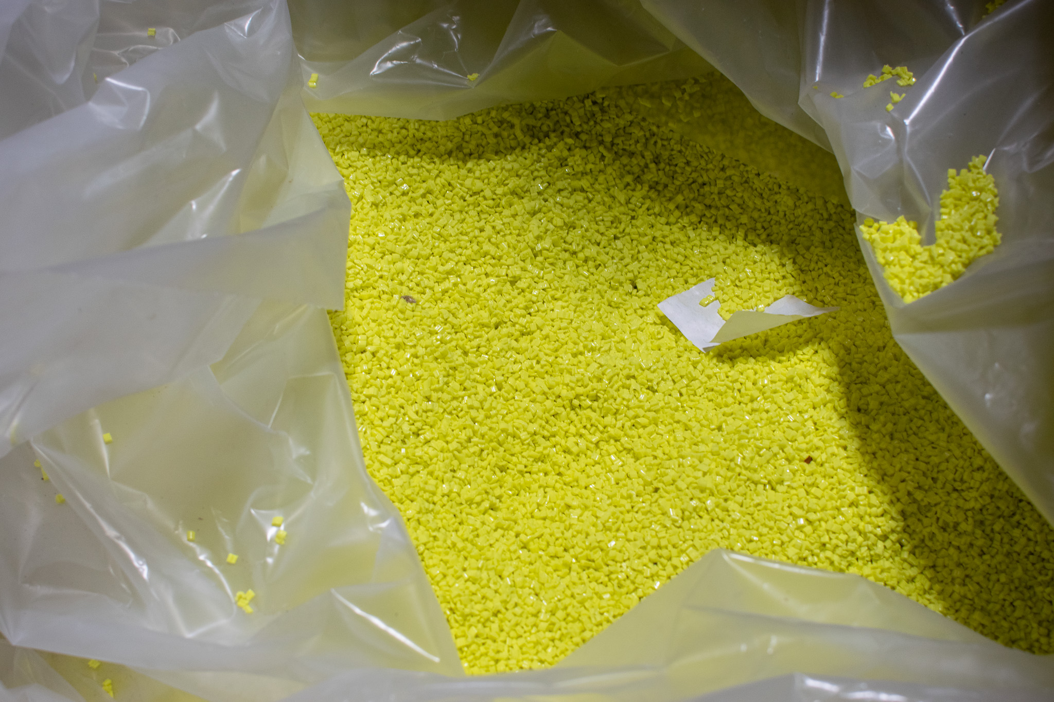Plastic bag filled with bright yellow plastic pellets.